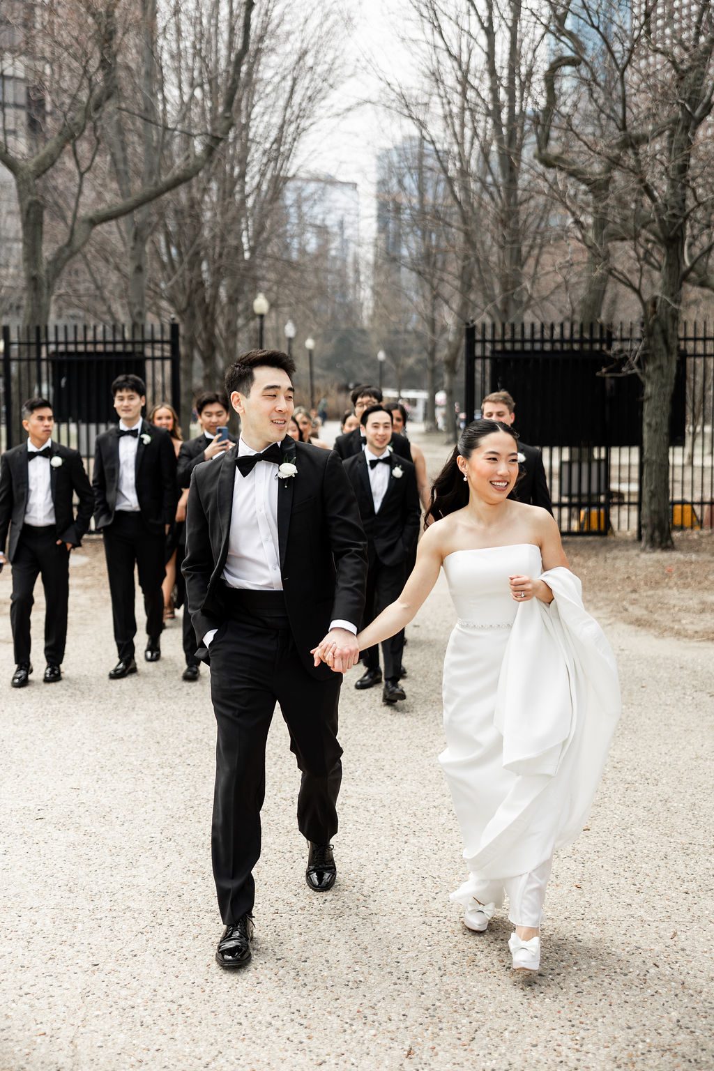 Bride and groom walk hand in hand with wedding party behind them