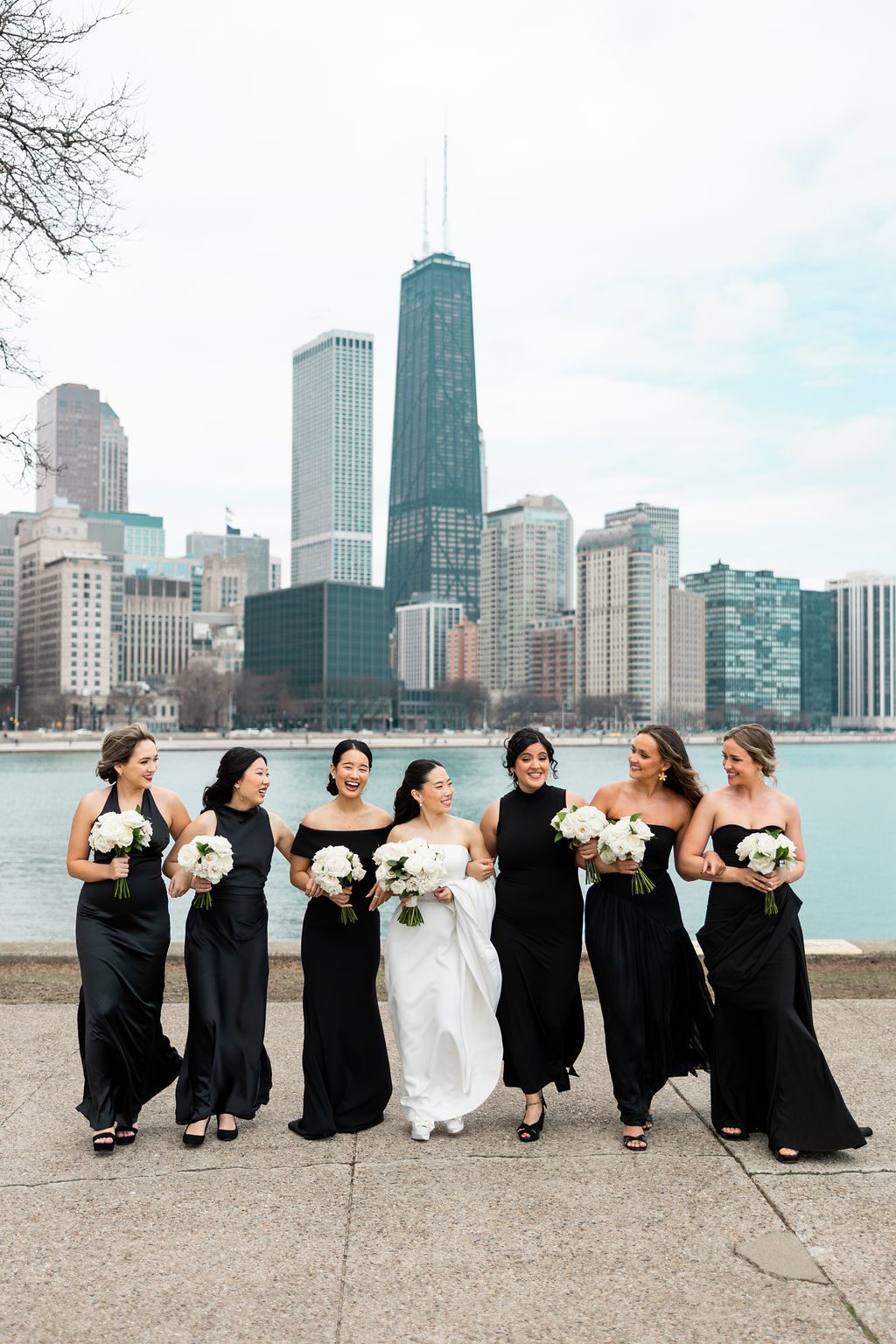 Bride with bridesmaids in long black dresses with Chicago backdrop