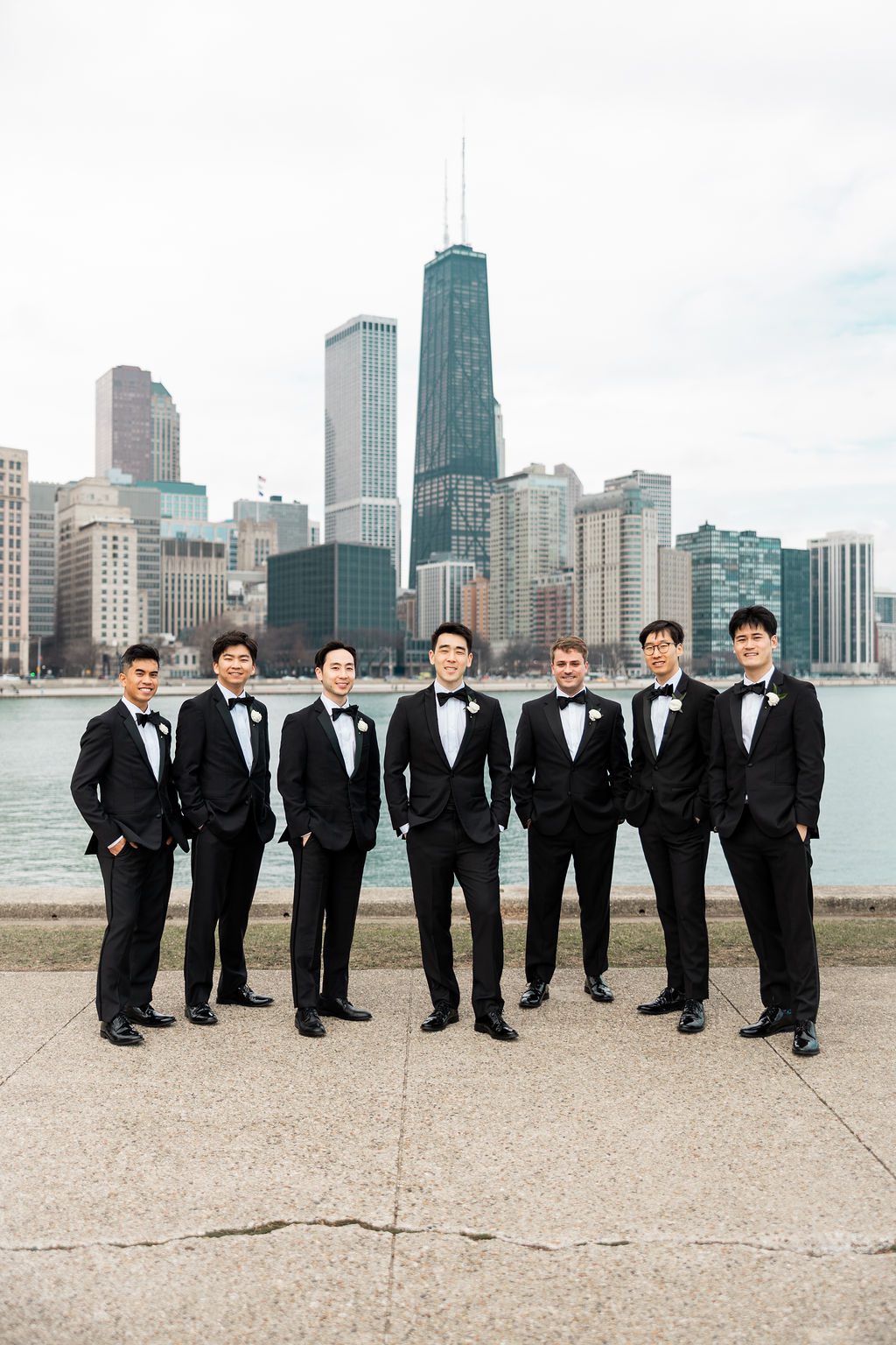 Groom and groomsmen in black tuxedos with Chicago skyline