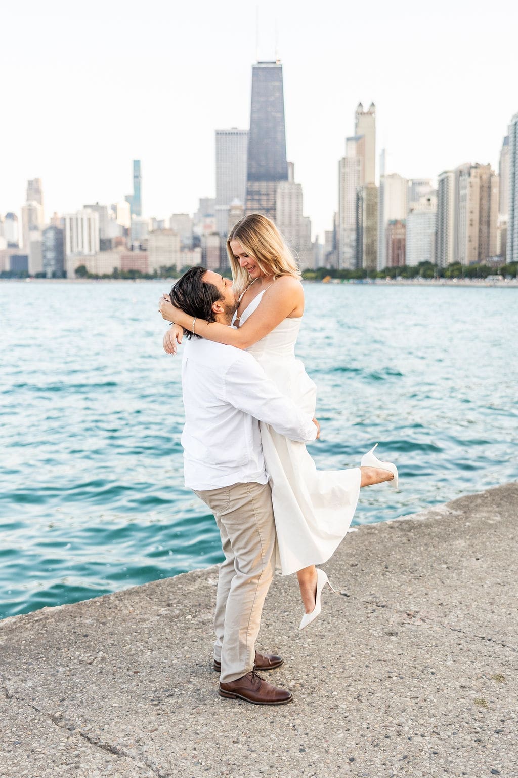 Man picks up woman during North Avenue Beach engagement photoshoot
