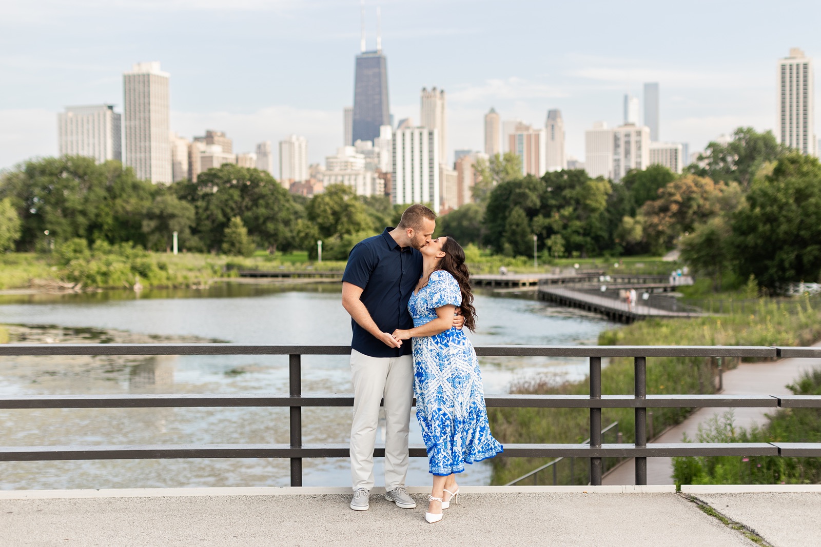 Man and woman kiss with Chicago skyline at their South Pond engagement photos